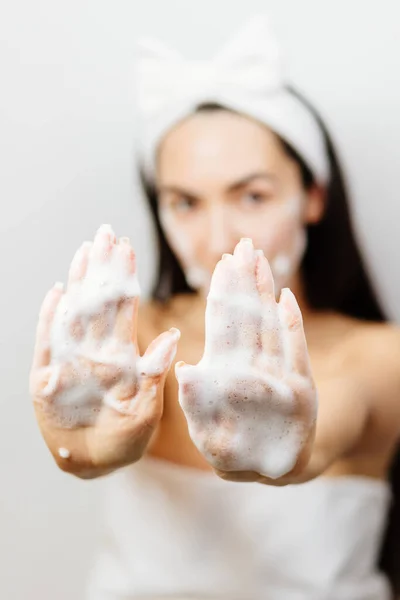 Woman applying facial foam on her face