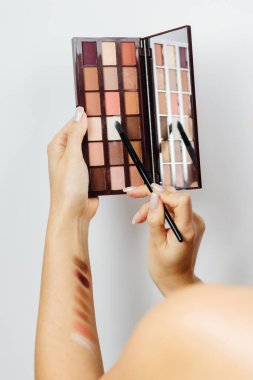 Makyaj için göz farı paletini seçen kadın