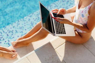 Havuzun kenarında dizüstü bilgisayarda çalışan serbest çalışan bir kadın.