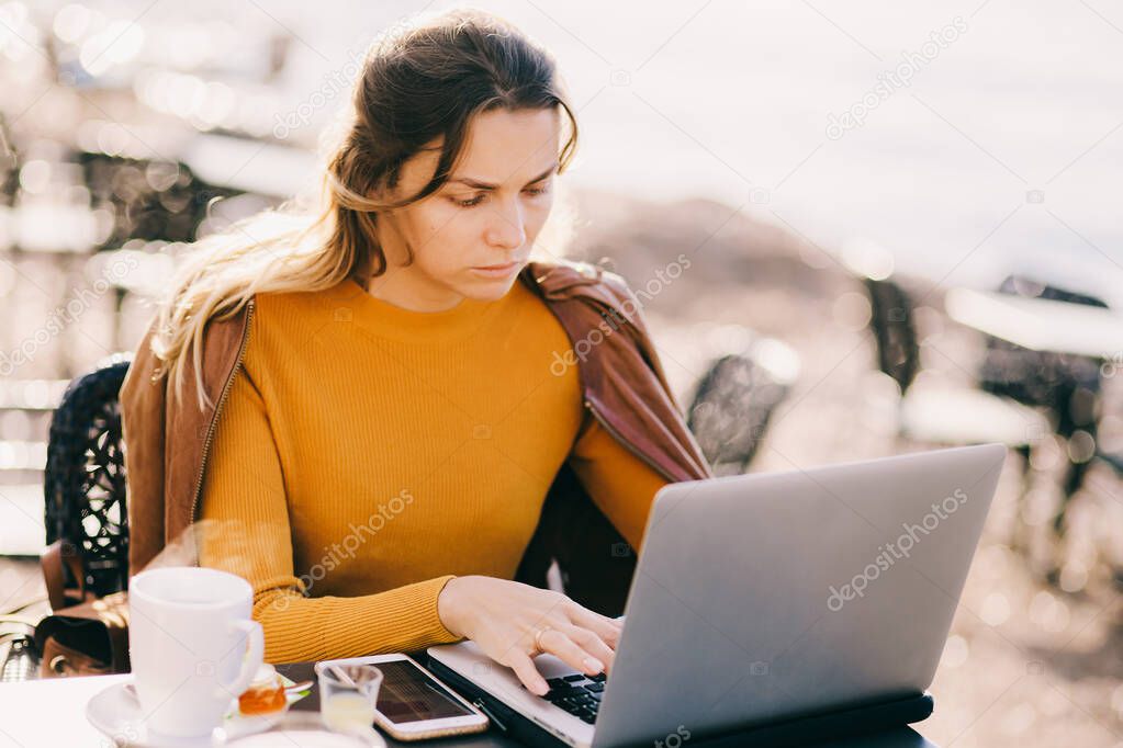 serious Female entrepreneur work on laptop outdoors in cafe