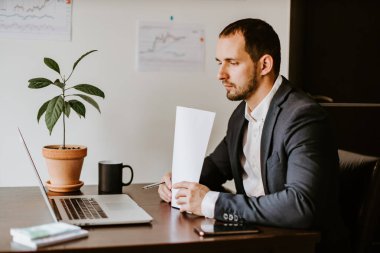 Ofiste dizüstü bilgisayarla çalışan konsantre iş adamı.