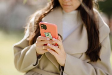 Gülümseyen kadın akıllı telefon kullanıyor ve online ödeme için para tutuyor.