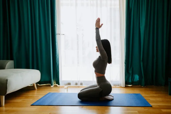 Junge attraktive Frau praktiziert Yoga zu Hause. Dehnübungen lizenzfreie Stockfotos