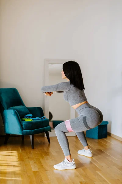 Attraente donna fitness che fa allenamento squat a casa Immagine Stock