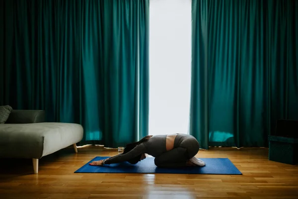 Junge Frau praktiziert Yoga zu Hause. Haltung üben lizenzfreie Stockfotos