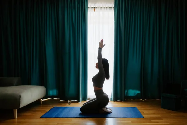 Junge Frau praktiziert Yoga zu Hause. Meditationspraxis Stockbild