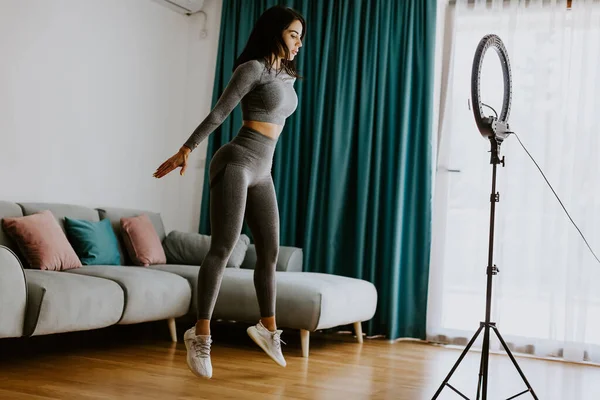 Aantrekkelijke vrouw virtuele workout thuis met behulp van smartphone — Stockfoto