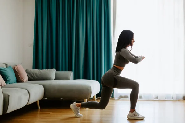 Patas de mujer atlética se abalanza ejercicio en casa, sentadillas. Entrenamiento en casa. — Foto de Stock