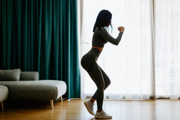 Atletische vrouw sport training thuis, squats. Thuistraining. — Stockfoto