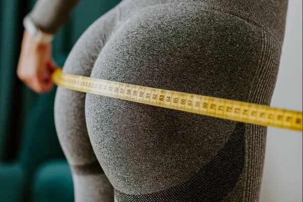 Fitness Woman Measuring butt With Tape at home. strong buttocks concept. — Stok Foto