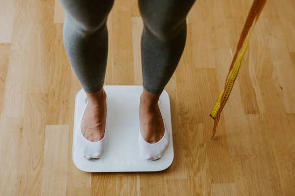 Vrouw stap op weegschaal voor het meten van lichaamsgewicht thuis. — Stockfoto