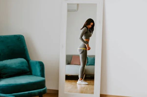 Fitness Vrouw meten lichaam met tape staan voor spiegel thuis — Stockfoto