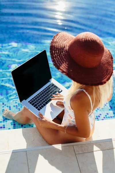 Жінка використовує ноутбук і працює дистанційно біля басейну — стокове фото