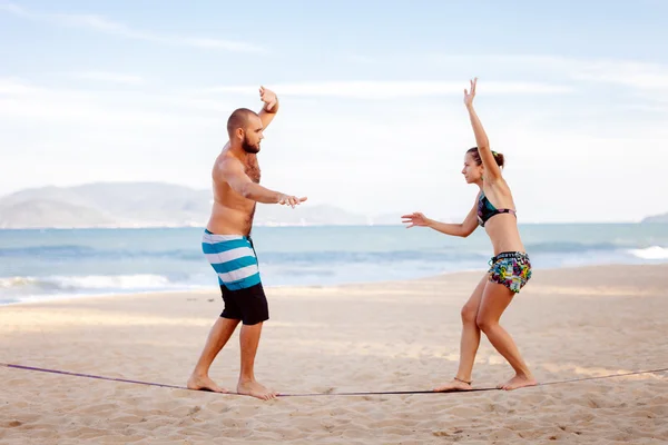 Ungt par balansera på slackline med havsutsikt — Stockfoto