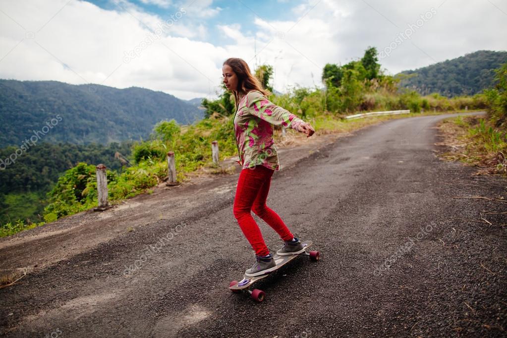 teenage girl skateboarding in mountains