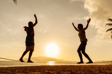 Genç çift sahilde Slackline Dengeleme