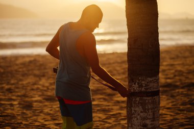 Genç kumsalda Dengeleme için slackline kurar