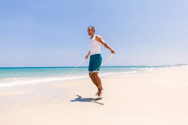 Homem bonito pulando na praia — Fotografia de Stock