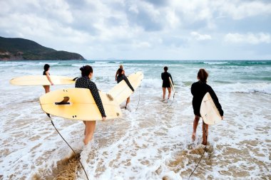 Unidentified surfers with surfing boards clipart