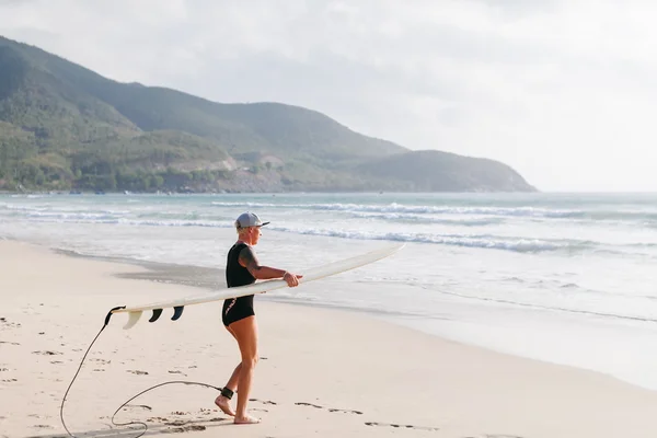 Surfing femeie cu bord de surfing pe plaja — Fotografie, imagine de stoc