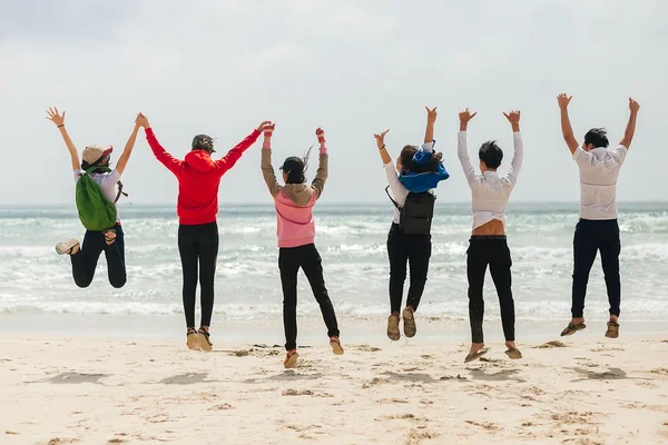 Asian teenagers jumping on the beach together — Stock Photo, Image