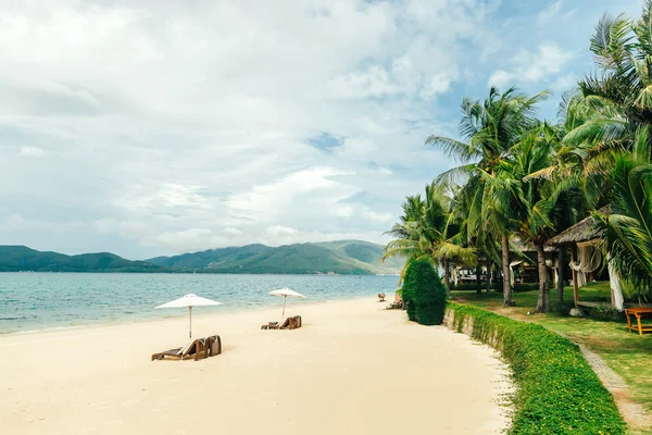 Pantai pasir putih dengan tempat tidur matahari dan telapak tangan, Hon Tam, Nha Trang harb Stok Lukisan  
