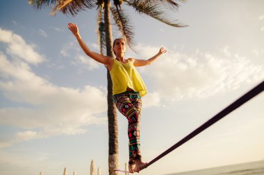 teenage girl  balancing on slackline with sky view clipart