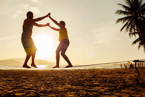 Genç çift sahilde Slackline Dengeleme