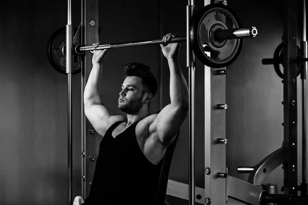 Culturista chico en gimnasio con pesos pesados monocromo — Foto de Stock