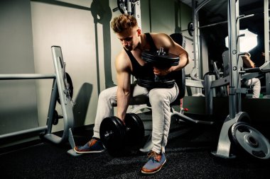 güçlü vücut geliştirmeci atlet spor salonunda ağır dumbbells ile