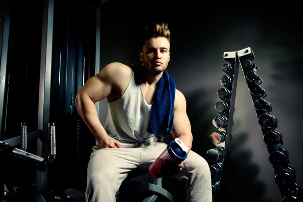 Strong bodybuilder athlete with protein shaker and towel — Stock Photo, Image