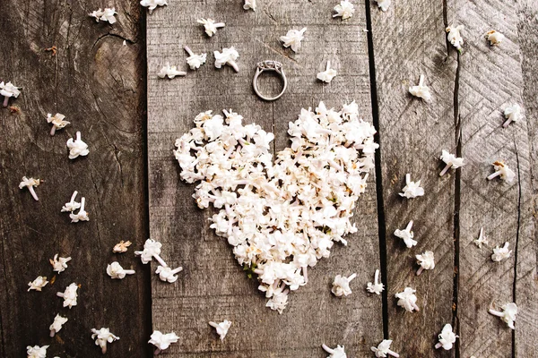 Fleurs en forme de coeur blanc doux avec anneau sur table en bois — Photo