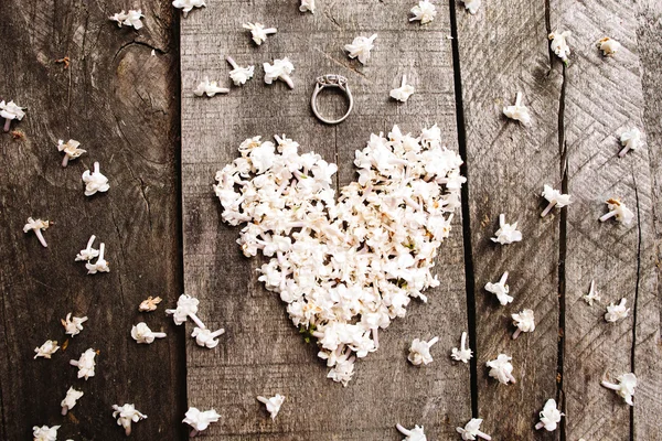 Delicato bianco fiori a forma di cuore con anello sul tavolo di legno Foto Stock Royalty Free