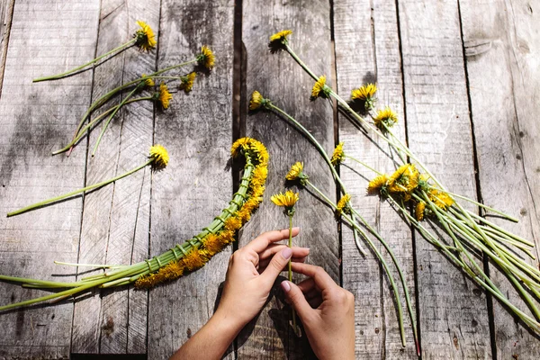 Corona de dientes de león flores hechas a mano sobre tabla de madera — Foto de Stock