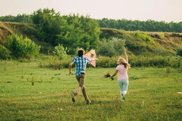 Encantador casal jogar com pipa de ar no prado verde — Fotografia de Stock