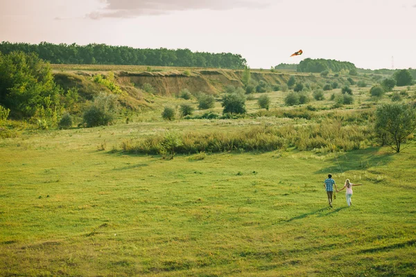 Lovely couple play with sky air kite at green meadow — Stock Photo, Image