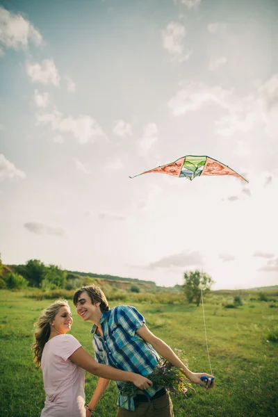 Lindo casal sorriso no ar pipa com céu dragão — Fotografia de Stock