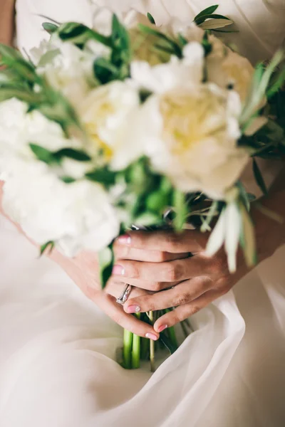 Mãos nupciais com anel de casamento e buquê — Fotografia de Stock