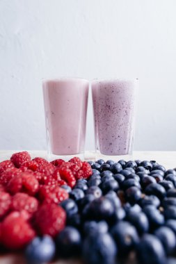 Ahşap masa üzerinde taze çilek ile Ahududu ve blueberry smoothie