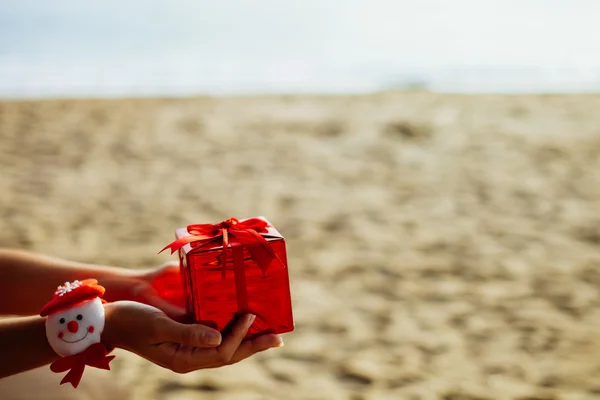 Presente de Natal em caixa vermelha na praia — Fotografia de Stock