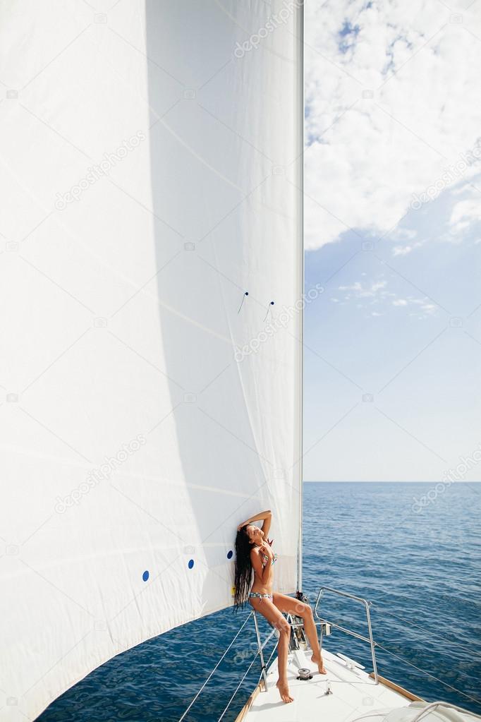sexy girl in swimwear on yacht under big white sail