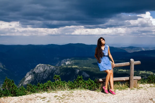 Mulher relaxar no pico da montanha com céu chuvoso — Fotografia de Stock