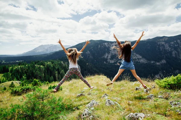 Iki kız mutlu dağlarda atlamak — Stok fotoğraf