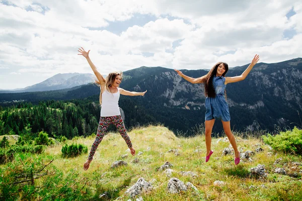 Iki kız mutlu dağlarda atlamak — Stok fotoğraf