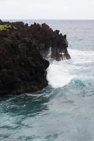 Kraschar vågor på vulkaniska bergarter — Stockfoto