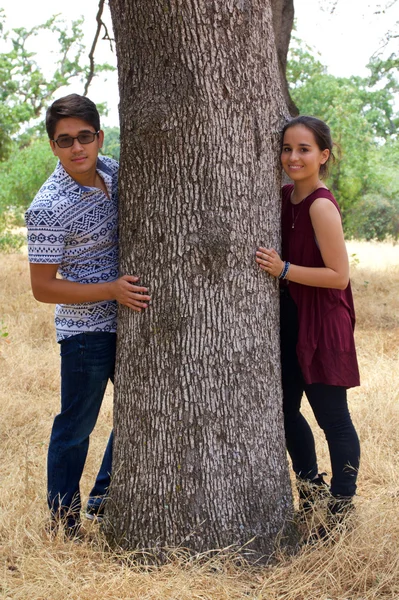 Adolescent petit ami et petite amie dans un parc à côté d'un arbre — Photo