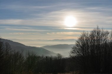Gün batımında dağların arasındaki vadiyi sis kaplıyor.