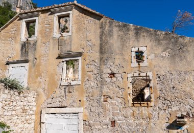 Harap olmuş ve çorak arazide zar zor ayakta duran eski bir duvar.