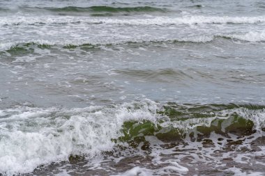 Köpüren deniz dalgaları kıyıya akıyor.