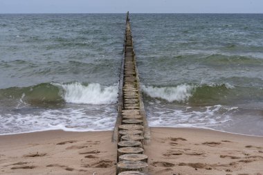 Deniz dalgaları eski bir ahşap dalgaya çarpıyor.